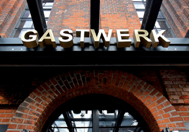 Eingang des Gastwerk Hotels Hamburg mit Schriftzug über dem Backsteinbogen